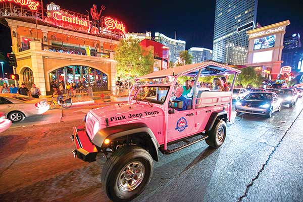 Tour guide and guests riding along the Las Vegas Strip at night on the Pink Jeep Tours Bright Lights Tour.