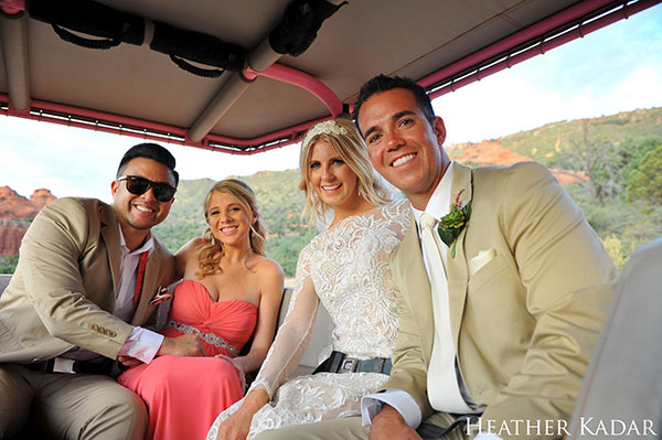 Close-up of bride, groom, best man and maid of honor sitting in backseat of Pink Jeep with Sedona in background