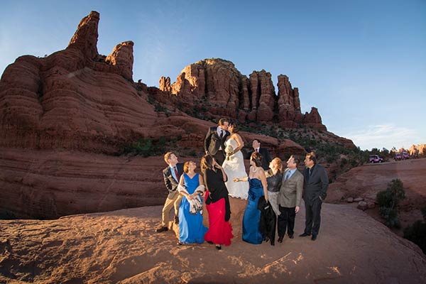 Wedding party with bride and groom kissing in late afternoon sunlight at Chicken Point, Sedona, AZ
