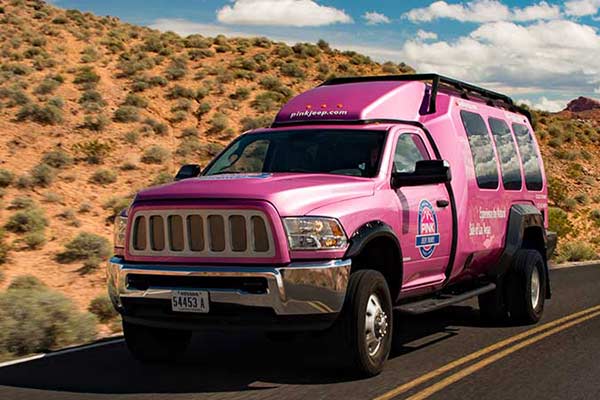 Close-up of Pink Adventure Tour Trekker vehicle on highway during Las Vegas-Grand Canyon West tour.