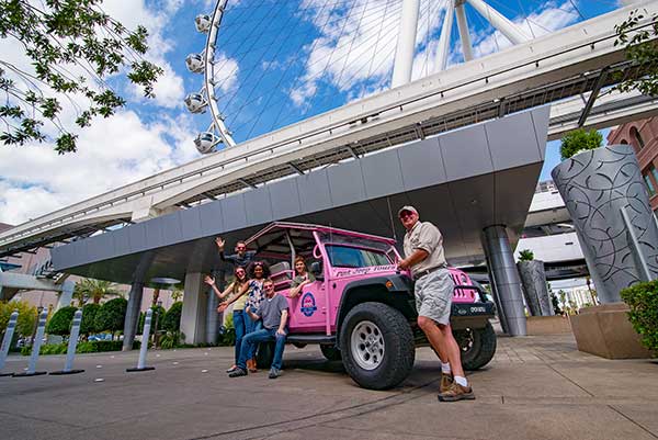 Las Vegas tour group standing by Pink Jeep parked by High Roller wheel