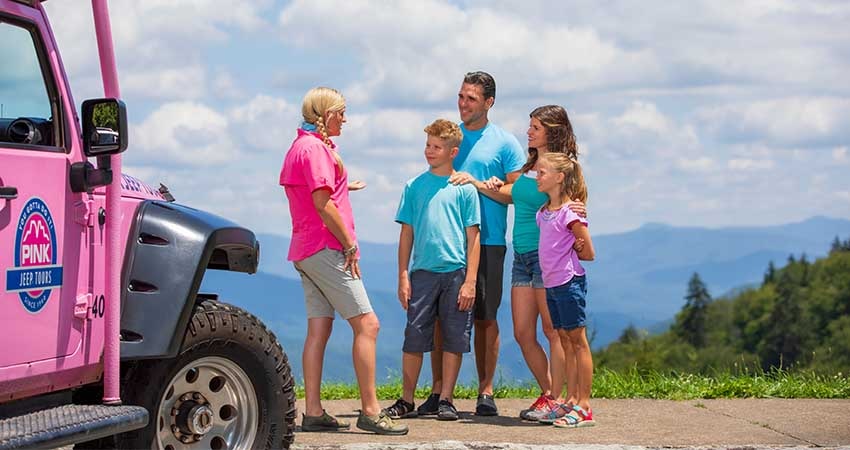 Newfound Gap tour guide talking with family beside a Pink Jeep with Smoky Mountains in background