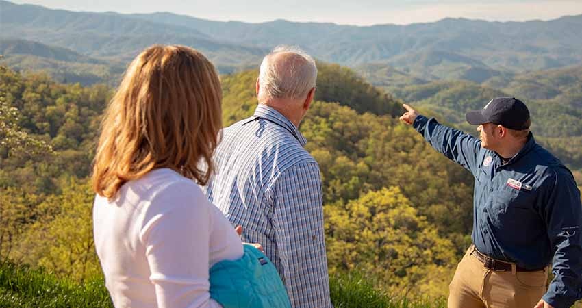  Pink® Jeep® tour guide pointing out the Smoky Mountain ridgelines to couple on Foothills Parkway Smoky Mountains tour.