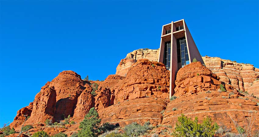 Chapel of the Holy Cross built into red rocks of Sedona with vibrant blue sky in background