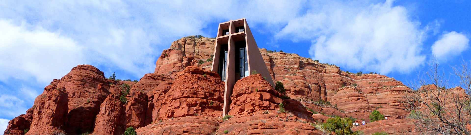 Chapel of the Holy Cross nestled into Sedona's red rocks with blue sky white clouds in back