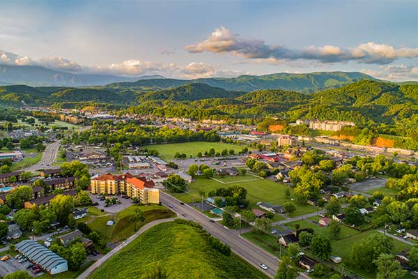 Aerial drone shot of Pigeon Forge and Sevierville, TN surround by vibrant green foothills of Smoky Mountains
