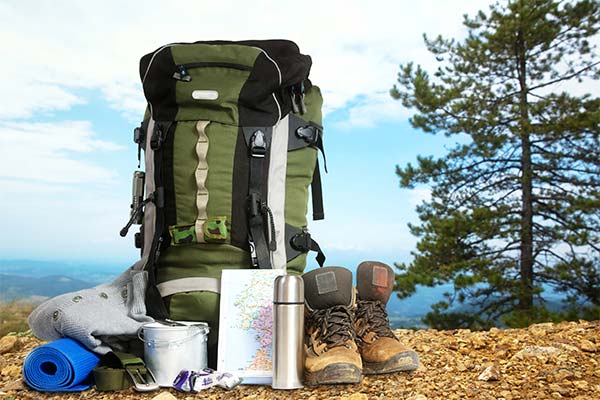 Hiking essentials with daypack and hiking shoes picture at top of mountain overlook