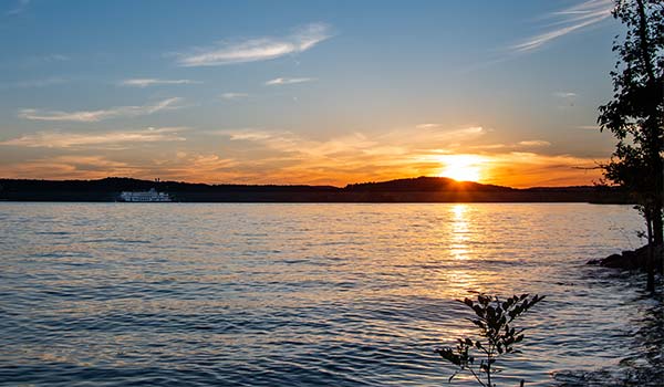 Beautiful golden sunset over Table Rock Lake with the Branson Belle parked along the shoreline in the distance.