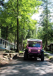 Frontal view of Pink Jeep Wrangler on road between newly restored cabins in Daisy Town, Elkmont Ghost Town, Smoky Mountains.