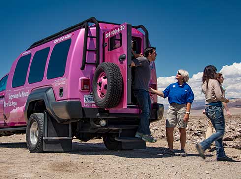 Guests exiting Pink Jeep Tour Trekker parked by the Devil's Golf Course, Death Valley National Park, CA.