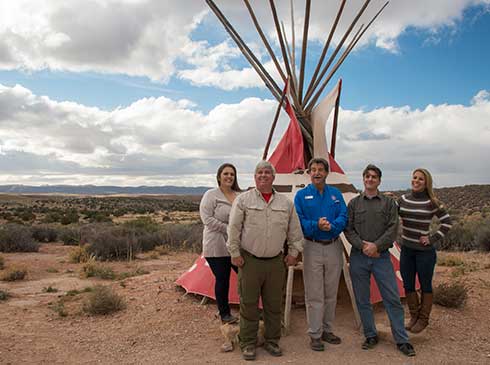 Group photo of Pink Jeep tour guide and guests in front of Native American tipi at Eagle Point, Grand Canyon West Rim