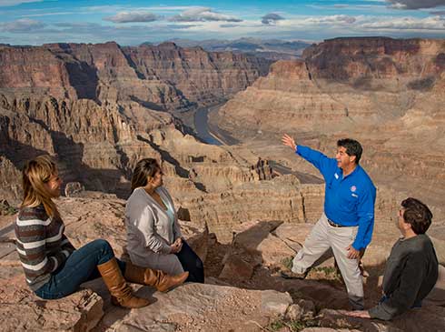 Pink® Jeep® tour guide interpreting a view of the Colorado River and Grand Canyon West Rim for guests.