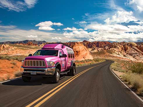 Pink® Jeep® Tour Trekker driving up two-lane road in Valley of Fire State Park, NV
