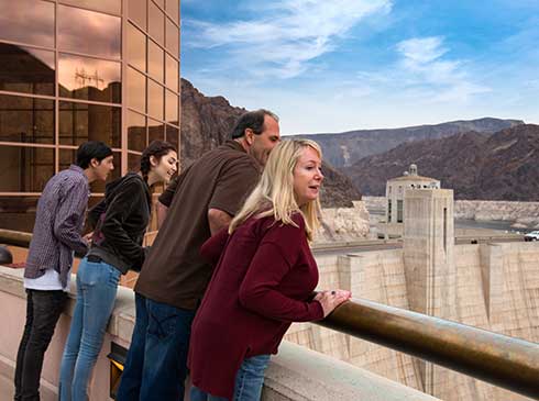Four tour guests looking over rail at Hoover Dam in Las Vegas, Nevada