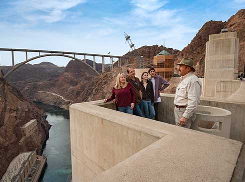 Guide talking to group at observation point on Hoover Dam with Colorado River below