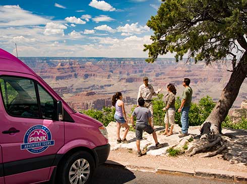 Pink Jeep interpretive guide talking with guests at Grand Canyon viewpoint, Mercedes Sprinter parked nearby
