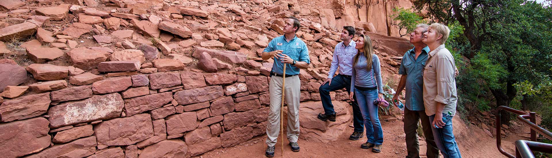 Pink Adventure Tour guide explaining the cliff dwellings at Honanki Heritage Site to guests, near Sedona, AZ.