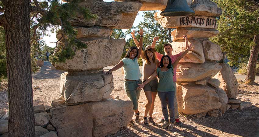 Four people posing by the rock pillars at Hermits Rest, Grand Canon National Park during Pink Jeep's Hermits Rest Tour.
