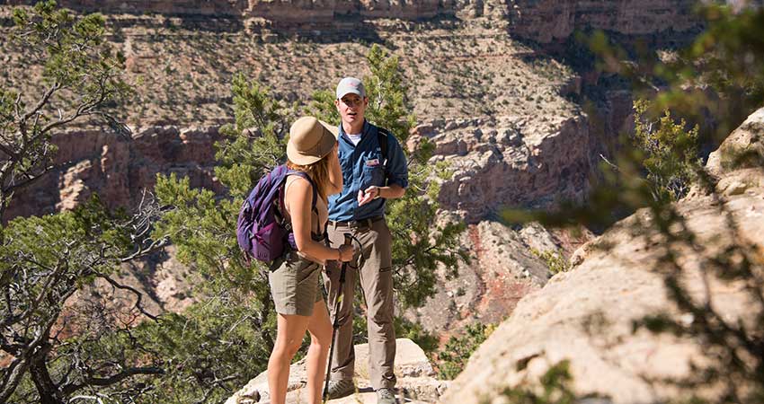 Pink® Jeep® tour guide and client standing along the edge of the Grand Canyon's Hermit Trail during the Hermit's Rest tour.