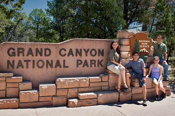 Family in front of Grand Canyon National Park Sign