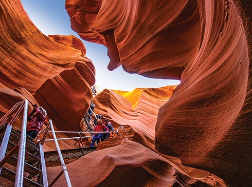 Pink® Jeep® tour guests descending steep ladder into Lower Antelope Canyon, Navajo land east of Page, AZ