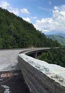 Great Smoky Mountains National Park Foothills Parkway bridge, with green forest, blue sky and white clouds