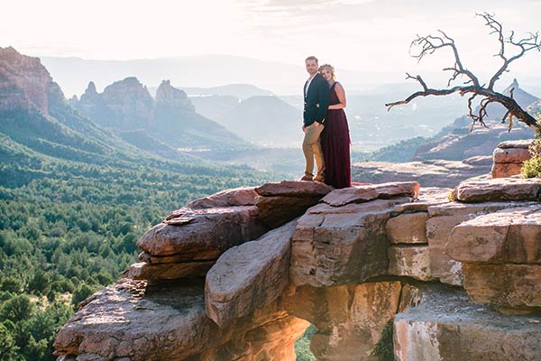Bride and groom standing on ledge of Merry-Go-Round Rock, with Sedona landscape in background