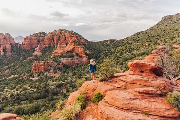 Woman standing on top of Merry Go Round Rock with views red rock country.