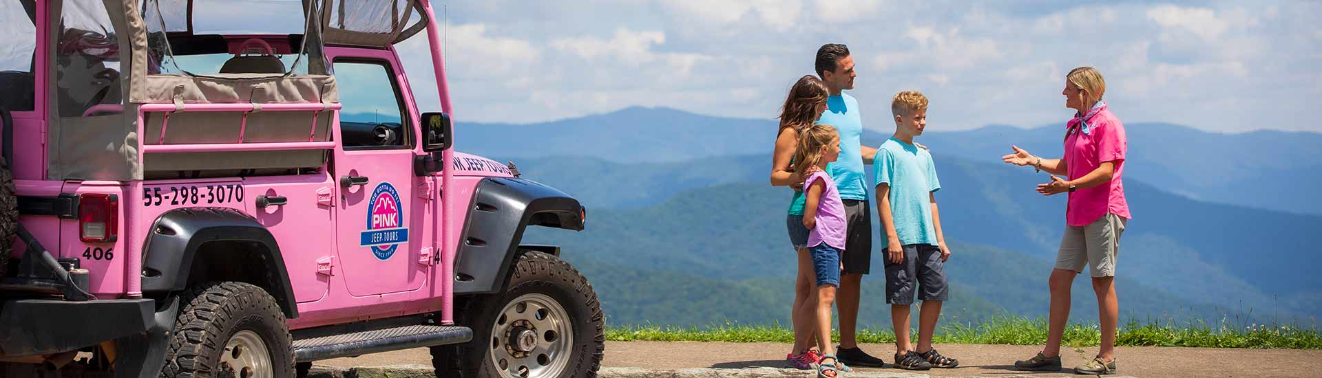 Newfound Gap tour guide talking to guests next to Pink® Jeep®, with Smoky Mountains blue ridge in background