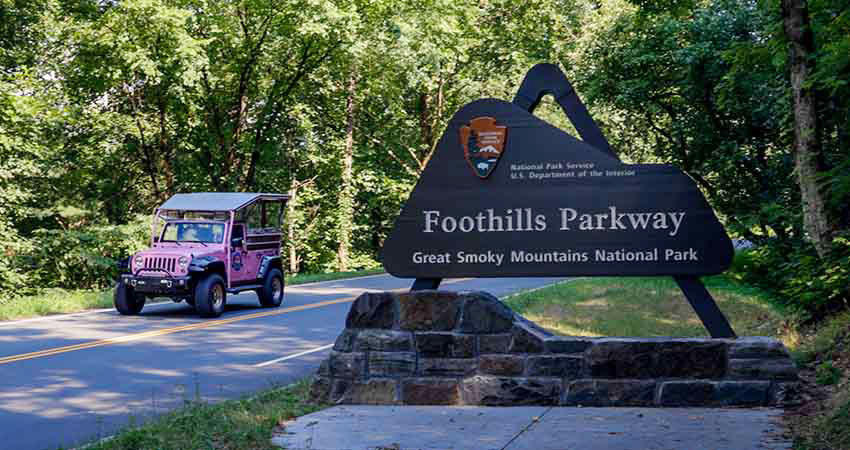 Pink® Jeep® vehicle passing the Foothills Parkway sign in Great Smoky Mountains National Park, TN