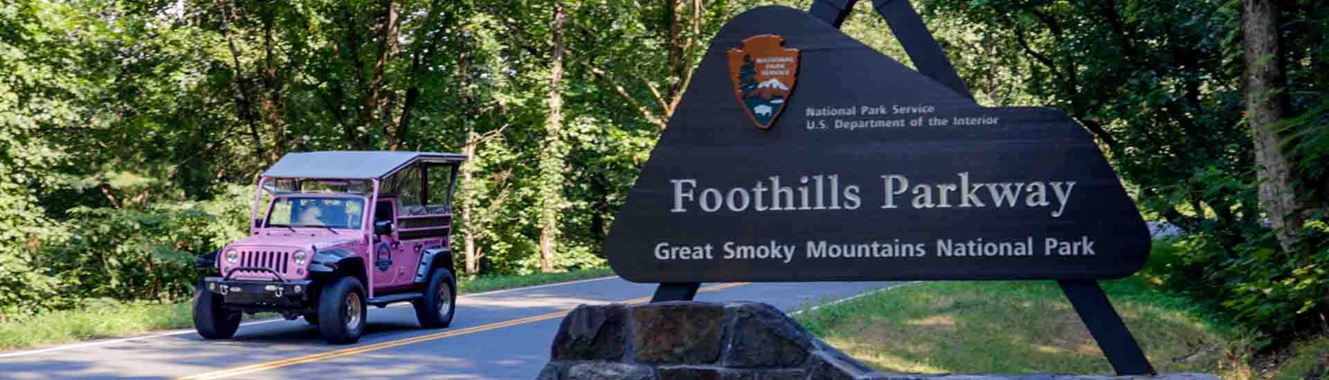 Pink® Jeep® vehicle driving past the Foothills Parkway sign, Great Smoky Mountains National Park, TN