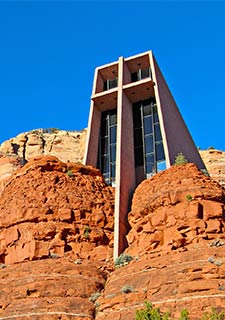 Chapel of the Holy Cross nestled into the red rocks in Sedona, Arizona with blue sky