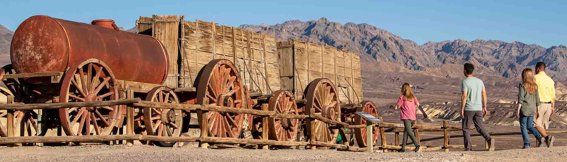 Pink Adventure Tours Death Valley Tour guests walking towards Twenty-Mule Team Wagon, Harmony Borax Works, Death Valley