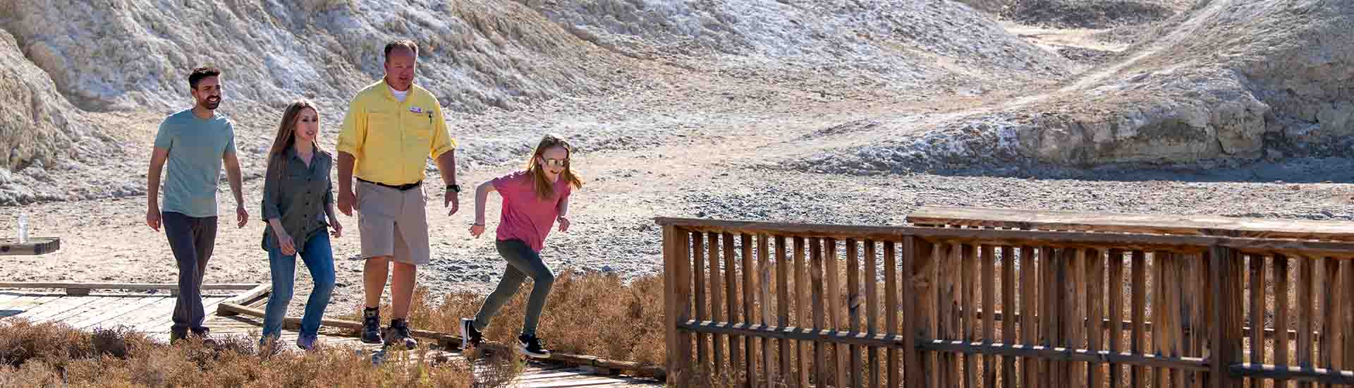 Pink Adventure Tour guide and guests, with girl running towards wooden bridge, Salt Creek Interpretive Trail, Death Valley National Park