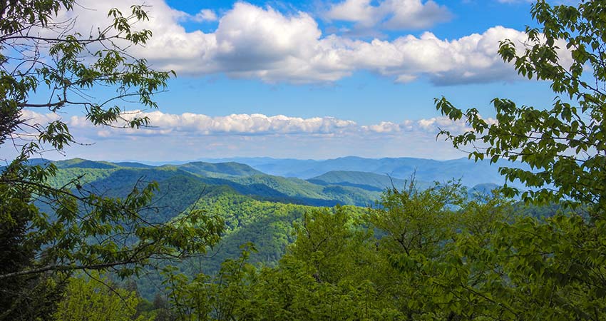 Beautiful rolling hilltops of the Great Smoky Mountains with blue sky and white clouds in distance, Foothills Parkway tour.