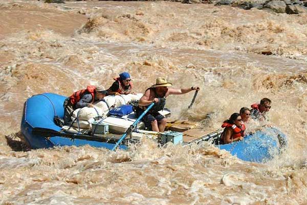 River guide and guests in raft maneuvering white water rapids of Colorado River, Grand Canyon West Rim