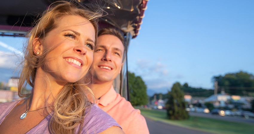 Close-up of male and female couple looking out a nd upward to the sky from a Pink Jeep Wrangler driving through Pigeon Forge, TN.