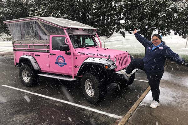 Adventure Guide Airika White poses by a Pink Jeep while snow falls in the Great Smoky Mountains.