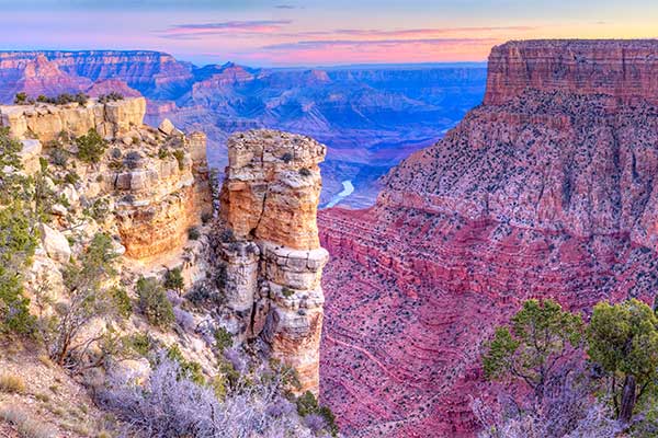 Beautiful pink sunrise looking out from Moran Point on Grand Canyon South Rim, with view of Colorado River below.