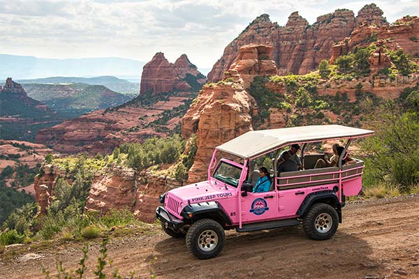 Tour guide and guests in Pink Jeep vehicle overlooking Sedona from Schnebly Hill Road on the Scenic Rim Tour.
