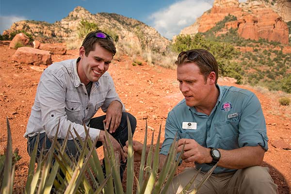 Pink® Jeep® Tours' guide explaining a cactus plant to guest on Coyote Canyons tour in Sedona, AZ.