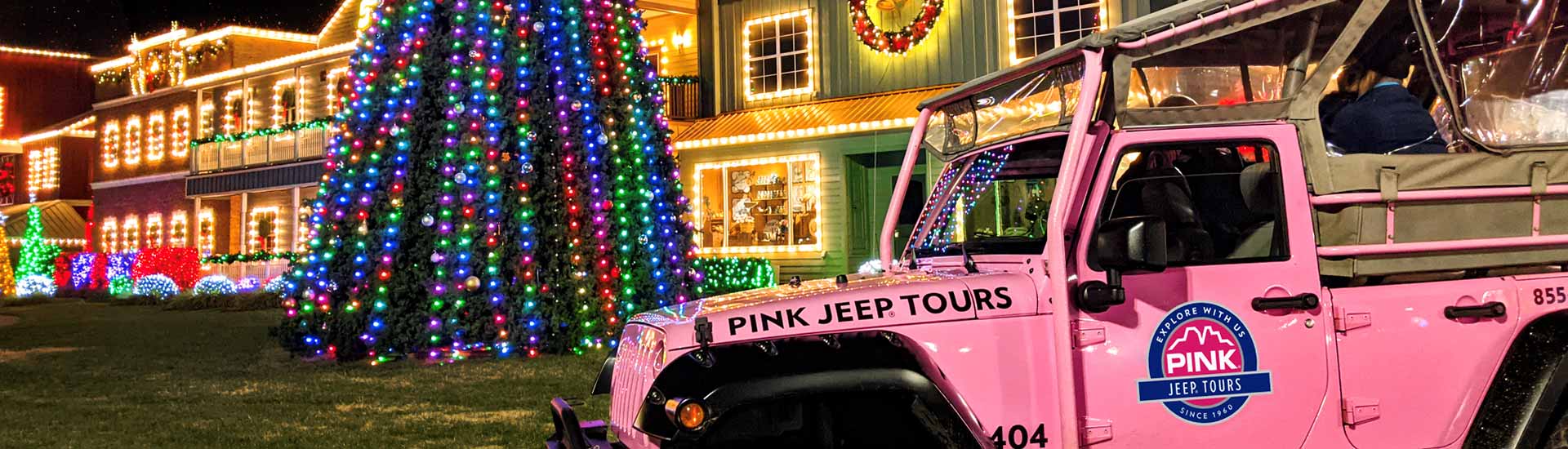 Horizontal close-up of side of Pink Jeep Tours' Jeep Wrangler in front of lighted Christmas display at Dolly Parton's Stampede, Pigeon Forge.