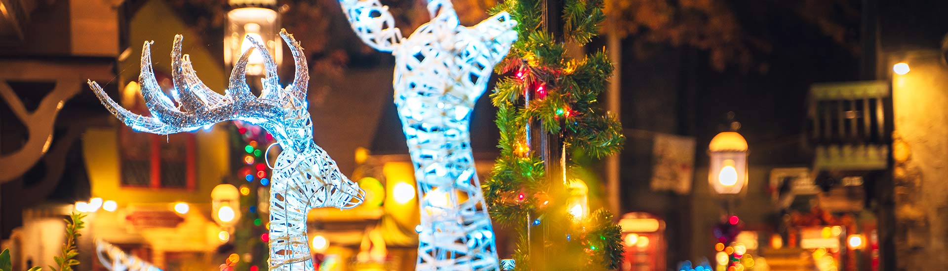 Two brilliantly lighted reindeer heads amid a warmly lit downtown Pigeon Forge Christmas plaza, Smoky Mountains, TN.