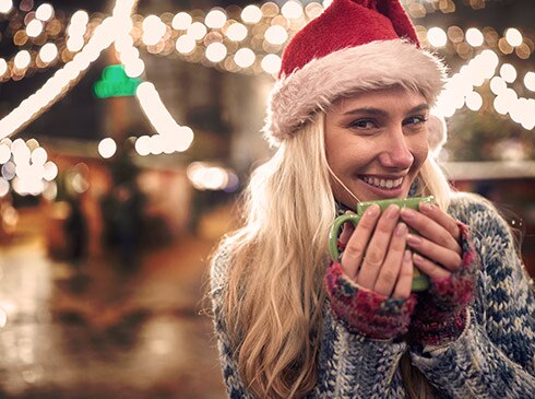 Woman in red Santa Clause hat drinking hot cocoa in a downtown Pigeon Forge Christmas plaza, Smoky Mountains.