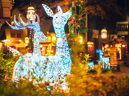 White light deer sculptures and holiday decorations in a warmly lit downtown plaza at night during Smoky Mountains Christmas.