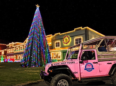 Pink Jeep Tours vehicle parked front of the 60-foot-tall, lighted Christmas tree at Dolly Parton's Stampede, Pigeon Forge, TN.