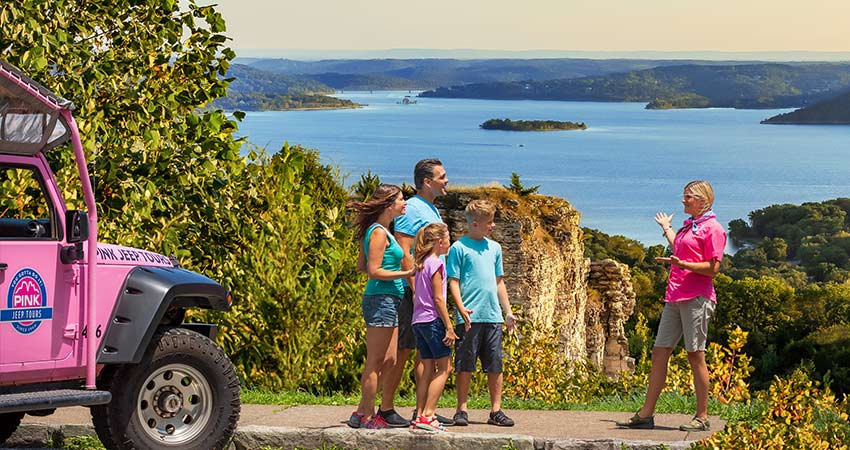 Pink® Jeep® Tours adventure guide talking with guests at Baird Mountain viewpoint, overlooking Table Rock Lake.