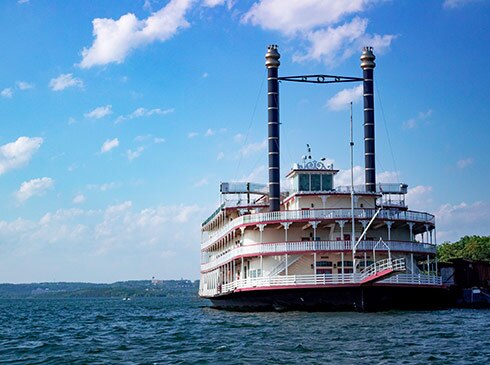 Close-up of the front of the Branson Belle Showboat parked along the shores of Table Rock Lake, with a beautiful blue sky above.