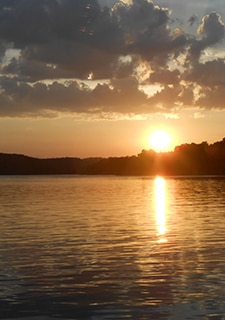 Fiery, gold sun sets below Branson's horizon and reflects on Table Rock Lake, Pink® Jeep® Tours Downtown to Mountaintop Sunset Tour.