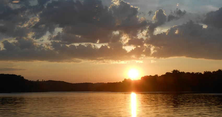 Beautiful gold sun sets across Table Rock Lake and behind the Branson hills in Branson, Missouri.